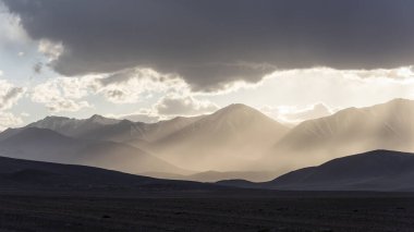 Karakul yakınlarında güneşli ve sisli dağlar, Tacikistan 'daki yüksek siyah dağlar, çöl ve vadi manzaralı..