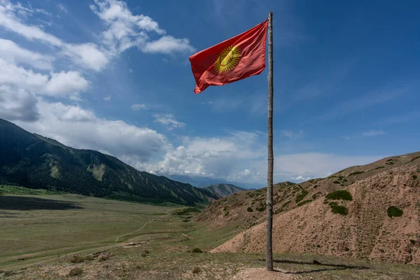 吉尔吉斯斯坦的国旗在山谷中飘扬 在夏日的群山中飘扬 天空蔚蓝 — 图库照片
