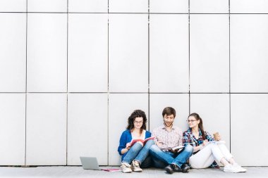 Kitaplar ve duvarın yanında katta oturan becerikli olan insanlar. Eğitim sosyal medya kavramı.