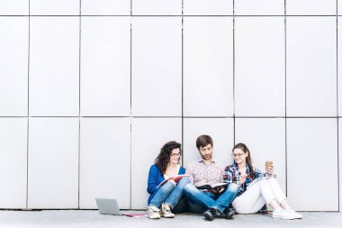 Kitaplar ve duvarın yanında katta oturan becerikli olan insanlar. Eğitim sosyal medya kavramı.