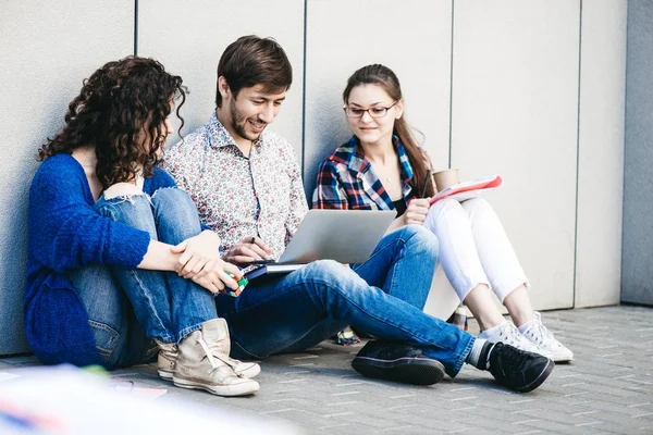 Kitaplar ve duvarın yanında katta oturan becerikli olan insanlar. Eğitim sosyal medya kavramı.