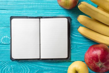 Taze meyve tarafından çevrili mavi ahşap arka plan üstünde not etmek