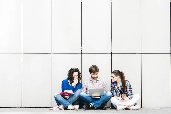 People with books and gadgets sitting on floor near the wall. Education social media concept.