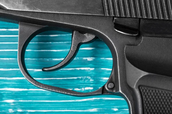 Black Gun on a blue wooden surface close-up. Studio shot. Top view — Stock Photo, Image