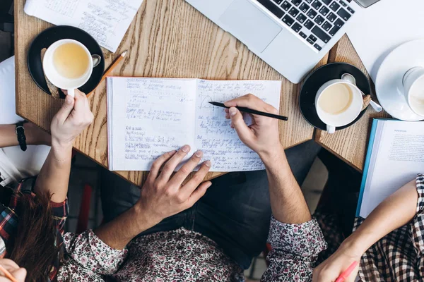 Visão superior das pessoas que estudam com livro, livro e laptop. Copos de café na mesa — Fotografia de Stock