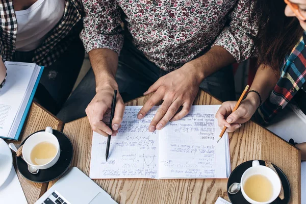 Visão superior das pessoas que estudam com livro, livro e laptop. Copos de café na mesa — Fotografia de Stock