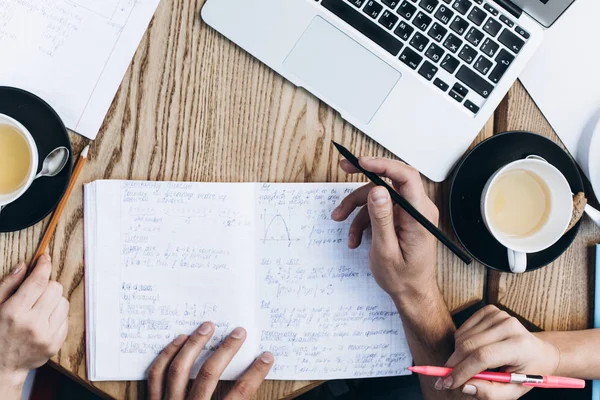 Visão superior das pessoas que estudam com livro, livro e laptop. Copos de café na mesa — Fotografia de Stock