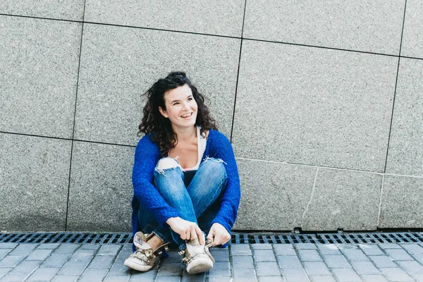 A menina está sentada junto à parede e amarrou os atacadores nos sapatos — Fotografia de Stock