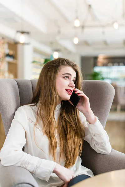 Menina bonita em um café falando em um celular — Fotografia de Stock
