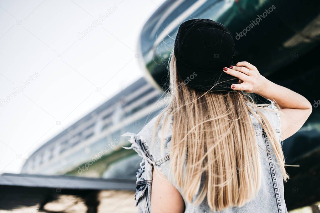 Beautiful tourist woman posing near the plane against jet engine 