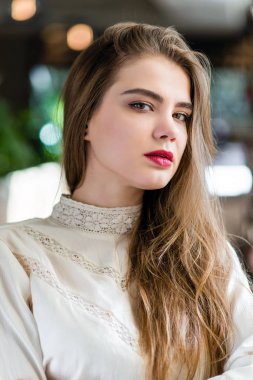 Profesyonel makyaj ve saç modeli restoranda oturan güzel genç kızla.