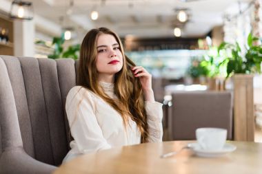 Profesyonel makyaj ve saç modeli restoranda oturan güzel genç kızla.