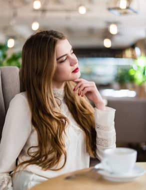 Profesyonel makyaj ve saç modeli restoranda oturan güzel genç kızla.