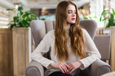 Profesyonel makyaj ve saç modeli restoranda oturan güzel genç kızla.