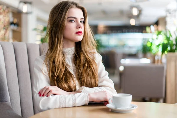 Profesyonel makyaj ve saç modeli restoranda oturan güzel genç kızla.