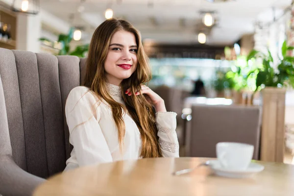 Profesyonel makyaj ve saç modeli restoranda oturan güzel genç kızla.