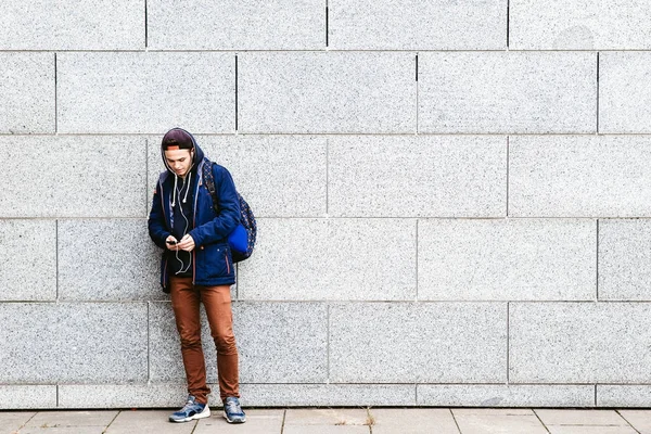 किशोरवयीन मुलगा संगीत ऐकणे आणि शहरी सेटिंगमध्ये फोन वापरणे — स्टॉक फोटो, इमेज