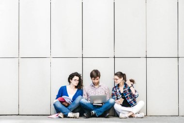 Kitaplar ve duvarın yanında katta oturan becerikli olan insanlar. Eğitim sosyal medya kavramı.