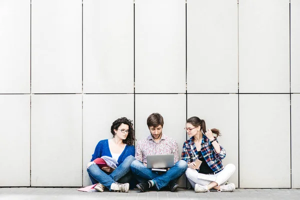 People with books and gadgets sitting on floor near the wall. Education social media concept.