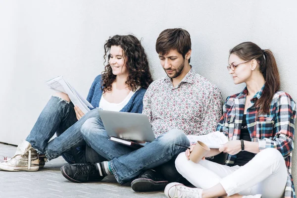 People with books and gadgets sitting on floor near the wall. Education social media concept.