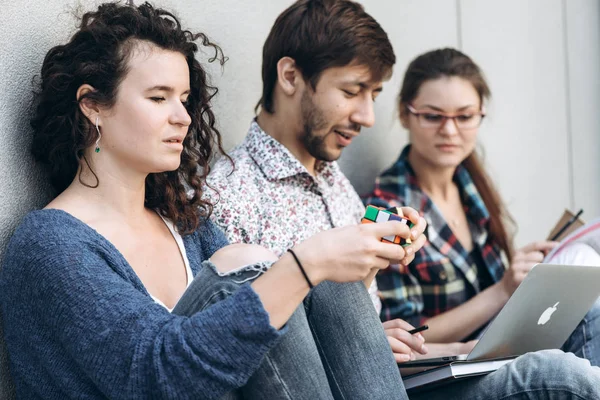 People with books and gadgets sitting on floor near the wall. Education social media concept.