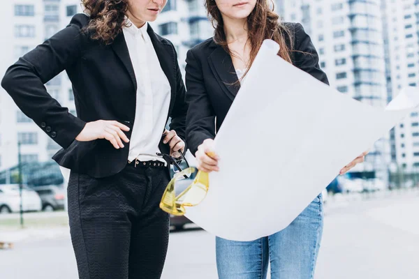 Dos mujeres de negocios en cascos de protección y gafas de seguridad se ven — Foto de Stock