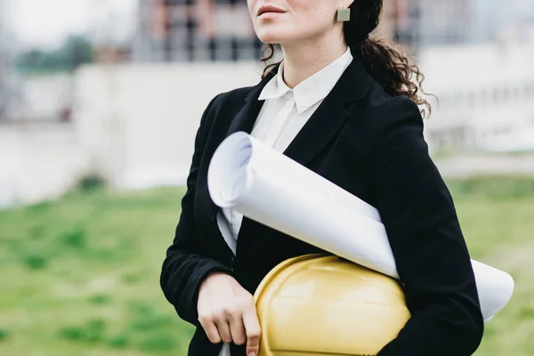 Primer plano de mujer ingeniera con casco amarillo en la mano contra ci — Foto de Stock