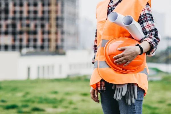 Gros plan de l'ingénieur femme avec casque jaune à la main contre ci — Photo