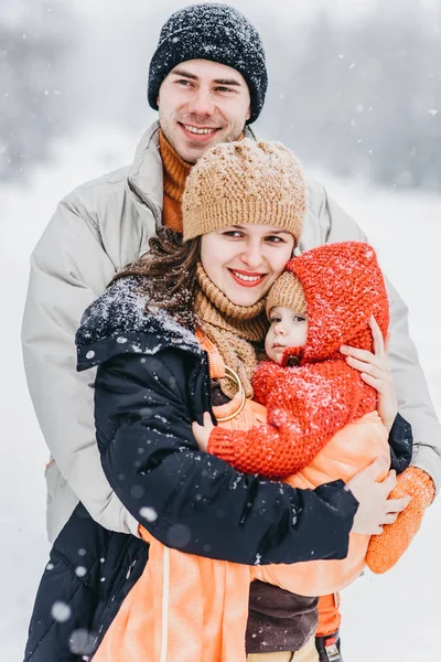 Cute family playing in the park in winter. A child in a sling on her mother — Stock Photo, Image