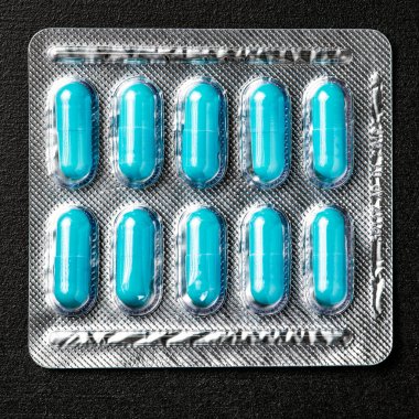 Siyah arka planda yer alan mavi kapsül hap ile paket