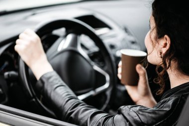 Bir araba sürüş sırasında bir kahve yudumlarken kadın.
