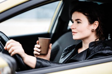 Bir araba sürüş sırasında bir kahve yudumlarken kadın.