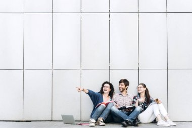 Kitaplar ve duvarın yanında katta oturan becerikli olan insanlar. Eğitim sosyal medya kavramı.