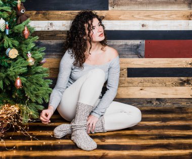 Bir Noel ağacı olan bir arka planda katta oturan güzel duygusal bir kız portresi. Noel ve yeni yıl kavramı. Kopya alanı