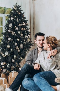 Mutlu çiftimiz Noel süsleri ve hediye kutuları ile beyaz odada. Noel ve yeni yıl kavramı