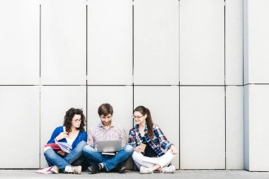 Kitaplar ve duvarın yanında katta oturan becerikli olan insanlar. Eğitim sosyal medya kavramı.