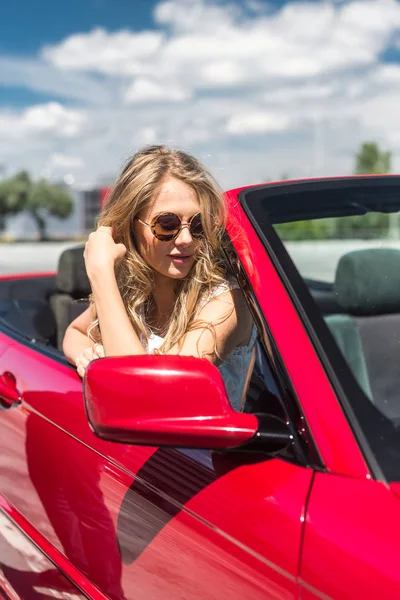 Beautiful blonde girl in a convertible red car. Sunny day
