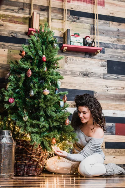 Beautiful woman in new year interior dresses up Christmas tree. Christmas and New Year concept