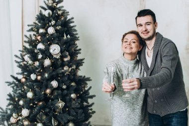 Genç güzel çift bardak şampanya ile Noel ağacı yakınındaki. Noel ve yeni yıl kavramı