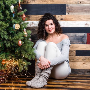 Güzel kız yılbaşı ağacının yanında oturuyor. Noel ve yeni yıl kavramı