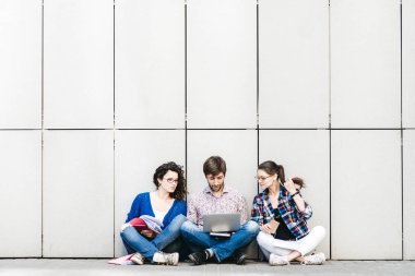 Kitaplar ve duvarın yanında katta oturan becerikli olan insanlar. Eğitim sosyal medya kavramı.