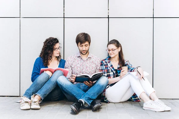 People with books and gadgets sitting on floor near the wall. Education social media concept.