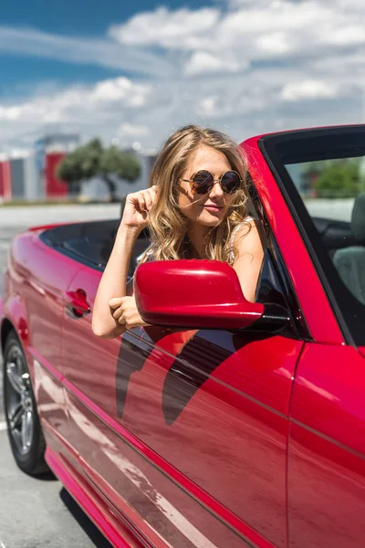 Beautiful blonde girl in a convertible red car. Sunny day