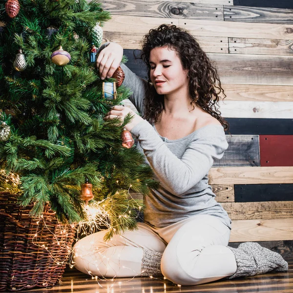 Beautiful woman in new year interior dresses up Christmas tree. Christmas and New Year concept