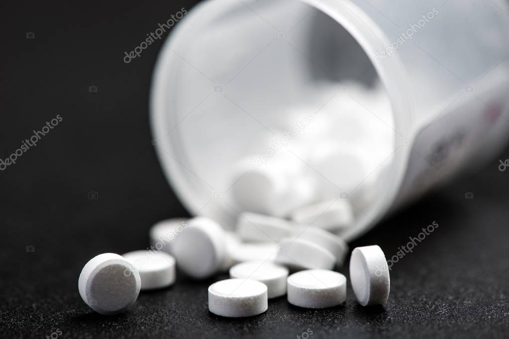 Medical white pills for the treatment and health care on a black background...