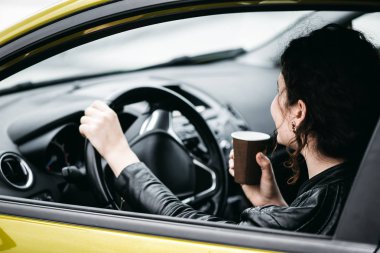 Bir araba sürüş sırasında bir kahve yudumlarken kadın.