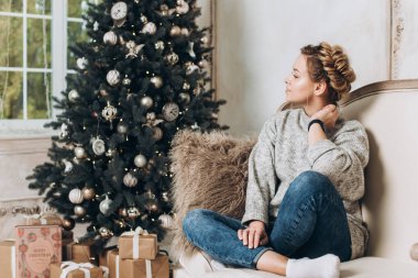 Noel ağacının yanında oturan güzel kız. Noel ve yeni yıl kavramı. Kopya alanı