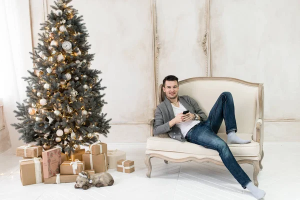 A handsome man lying on a sofa near a Christmas tree. Christmas and New Year concept