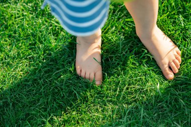 Barefooted child standing during walking  on green grass, outdoo