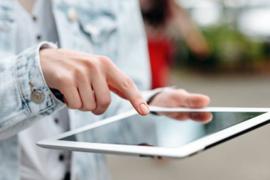 Closeup female hand with a ipad. Index finger pointing to screen
